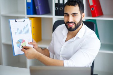 Masada oturan ve dizüstü bilgisayar kullanma office genç yakışıklı girişimci.