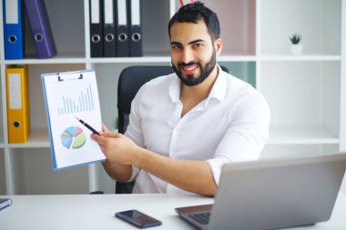 Ofiste bilgisayar üzerinde çalışan genç iş adamı.