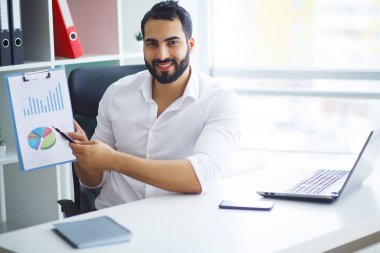 Masada oturan ve dizüstü bilgisayar kullanma office genç yakışıklı girişimci.