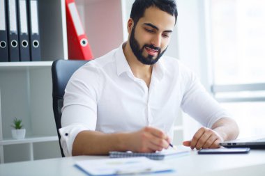 Masada oturan ve dizüstü bilgisayar kullanma office genç yakışıklı girişimci.