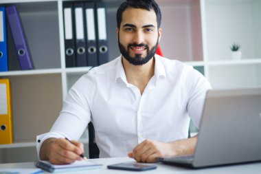 Ofiste bilgisayar üzerinde çalışan genç iş adamı.