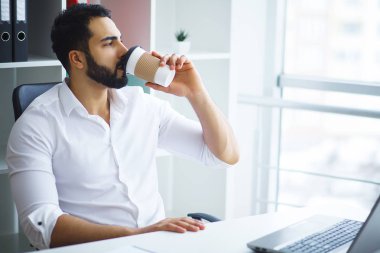 Masada oturan ve dizüstü bilgisayar kullanma office genç yakışıklı girişimci.