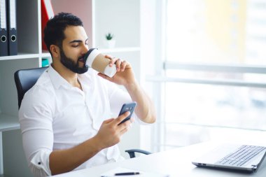 Ofiste bilgisayar üzerinde çalışan genç iş adamı.