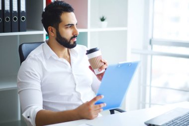 Ofiste bilgisayar üzerinde çalışan genç iş adamı.