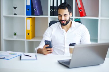 Ofiste bilgisayar üzerinde çalışan genç iş adamı.