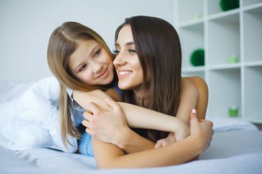 mutlu anne ve kızı yatakta yatan