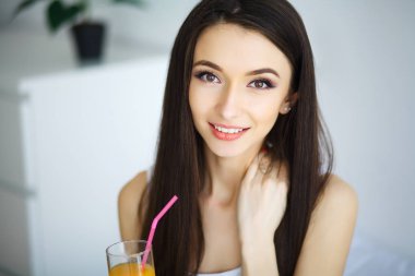 neşeli kadın yatağında oturmuş bir portakal suyu içme