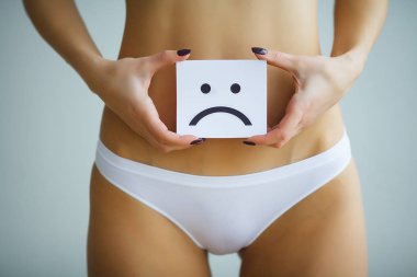 Kadın sağlığı. Kadın vücudu mide yakınındaki üzgün Smiley kartı tutan