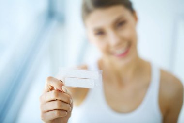 Diş beyazlatma. Şerit beyazlatma tutan güzel gülümseyen kadın. Yüksek çözünürlüklü görüntü