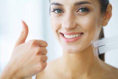 Diş beyazlatma. Şerit beyazlatma tutan güzel gülümseyen kadın. Yüksek çözünürlüklü görüntü