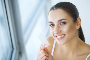 Diş beyazlatma. Şerit beyazlatma tutan güzel gülümseyen kadın. Yüksek çözünürlüklü görüntü