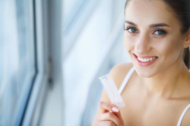 Diş beyazlatma. Şerit beyazlatma tutan güzel gülümseyen kadın. Yüksek çözünürlüklü görüntü