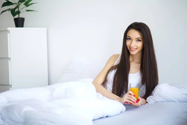 Vrolijke Vrouw Drinkt Een Sinaasappelsap Zittend Haar Bed Thuis — Stockfoto