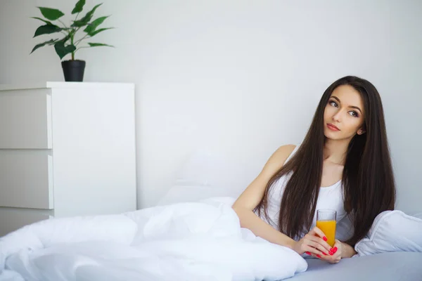 Radosna Kobieta Pije Sok Pomarańczowy Siedząc Łóżku Domu — Zdjęcie stockowe