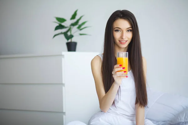 Vrolijke Vrouw Drinkt Een Sinaasappelsap Zittend Haar Bed Thuis — Stockfoto