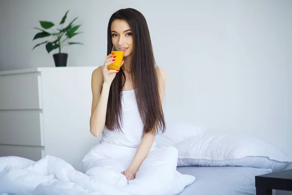 Fröhliche Frau Trinkt Orangensaft Sitzend Auf Ihrem Bett — Stockfoto