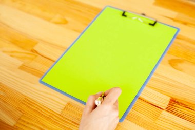 Bir klasörü bir yeşil renk kağıt ahşap masa arka plan üzerinde tutan office el. Boşaltmak. Metin için yer.