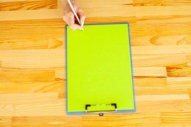 Office el a ağıl ile yeşil renk kağıt ve kalem ahşap masa arka plan üzerinde tutarak. Boşaltmak. Metin için yer.