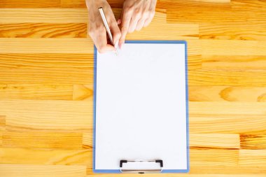 Office el a ağıl ile beyaz renk kağıt ve kalem ahşap masa arka plan üzerinde tutarak. Boşaltmak. Metin için yer.