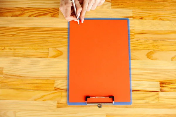 Office el a ağıl ile bir kırmızı renk kağıt ve kalem ahşap masa arka plan üzerinde tutarak. Boşaltmak. Metin için yer.