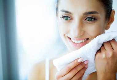 Sağlık ve güzellik. Beyaz dişler beyaz bir havlu elinde tutan güzel genç kız. Güzel bir gülümseme olan bir kadın. Diş sağlığı. Temiz ve taze bir cilt