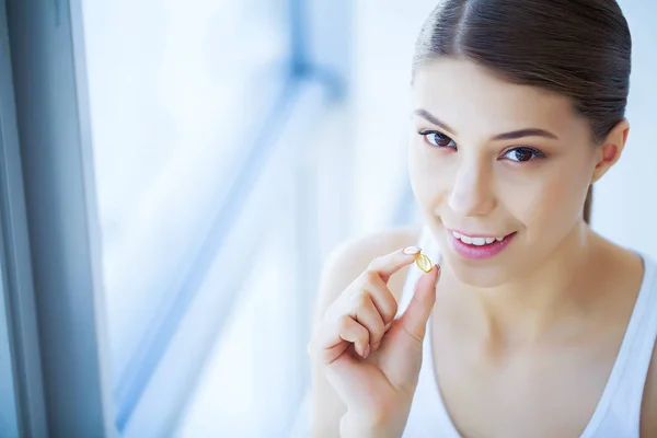 Health and Beauty. Vitamins. Beautiful Young Girl With White Teeth Holding A Pill In Hands. A Woman With A Beautiful Smile. Tooth Health.