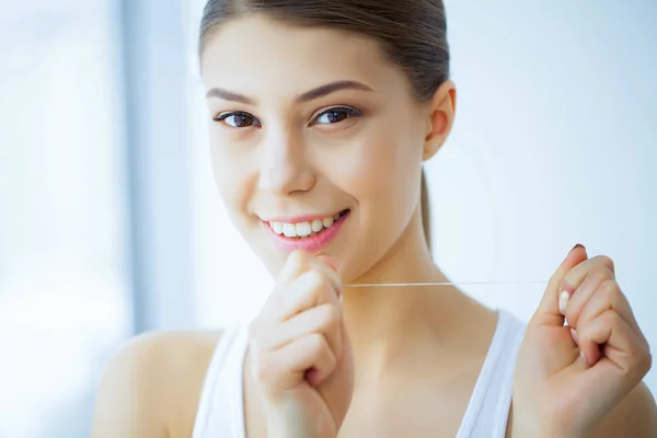 Health and Beauty. Beautiful Young Girl With White Teeth Cleans Teeth With Dental Floss. A Woman With A Beautiful Smile. Tooth Health