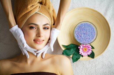 Güzellik ve bakım. Güzellik uzmanı yüz masaj yapar. Masaj masanın üzerinde yatan genç kadın. Güzel kız rahatlatıcı Spa salonda. Cilt bakımı yüz. Yüksek çözünürlük
