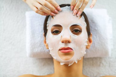 Güzellik. Yüz maskesi güzellik salonuyla güzel kadın. Masaj masaları üzerinde yalan. Saf ve taze bir cilt. Cilt Bakımı. Yüksek çözünürlük