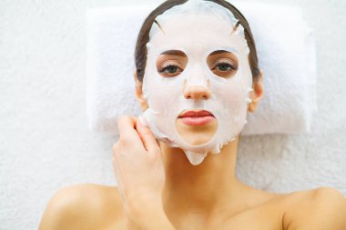 Güzellik. Yüz maskesi güzellik salonuyla güzel kadın. Masaj masaları üzerinde yalan. Saf ve taze bir cilt. Cilt Bakımı. Yüksek çözünürlük