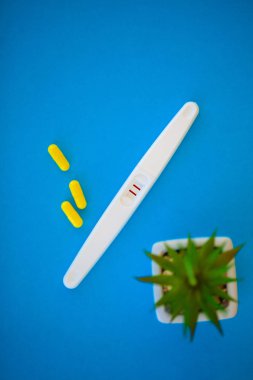 Sonuç olumlu olur. Hamilelik testi ve Doğum kontrol hapları Doğum kontrol kavramı mavi zemin üzerine yakın çekim