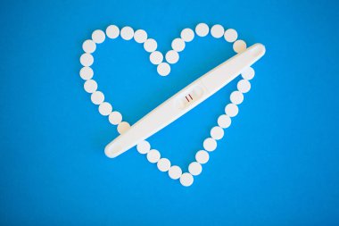 Gebelik planlama concep. Hamilelik testi pozitif iki çizgili ve mavi arka plan üzerinde Doğum kontrol hapı ile.