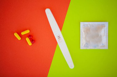 Hamilelik testi. Sonuç olumlu iki şeritler ve prezervatifle gebelik önleyici renkli arka plan, Doğum kontrol hapı, güvenli seks, sağlık concep