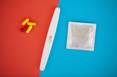 Hamilelik testi. Sonuç olumlu iki şeritler ve prezervatifle gebelik önleyici renkli arka plan, Doğum kontrol hapı, güvenli seks, sağlık concep