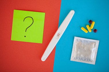 Hamilelik testi. Sonuç olumlu iki şeritler ve prezervatifle gebelik önleyici renkli arka plan, Doğum kontrol hapı, güvenli seks, sağlık concep