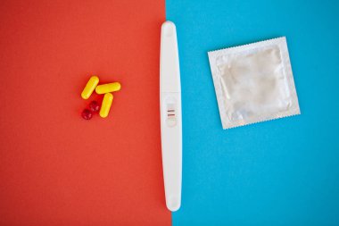 Hamilelik testi. Sonuç olumlu iki şeritler ve prezervatifle gebelik önleyici renkli arka plan, Doğum kontrol hapı, güvenli seks, sağlık concep