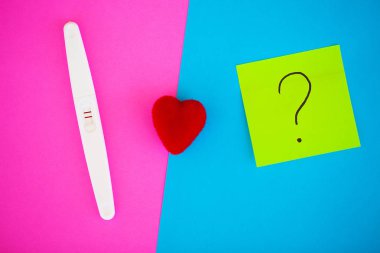 Hamilelik testi. Sonuç olumlu iki şeritler ve prezervatifle gebelik önleyici renkli arka plan, Doğum kontrol hapı, güvenli seks, sağlık concep