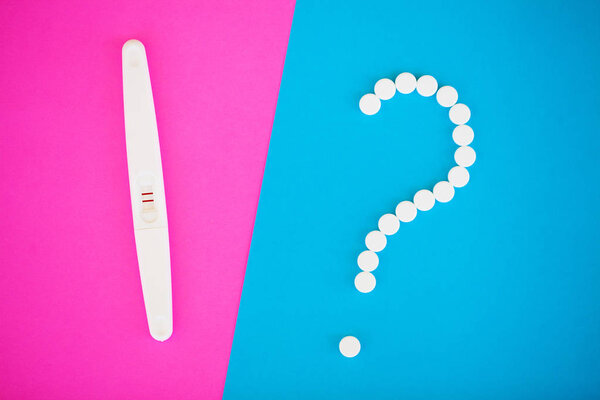 Тест на беременность. Результат положительный с двумя полосками и презервативом с контрацептивом на цветном фоне, противозачаточные таблетки, безопасный секс, концепция здравоохранения
