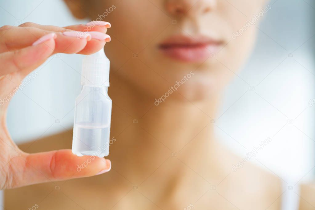 Vision And Medicine Concept. Young Girl Holds Eye Drops In Hands. Portrait of a Beautiful Woman with Green Eyes and Contact Lenses. Healthy Look. High Resolution
