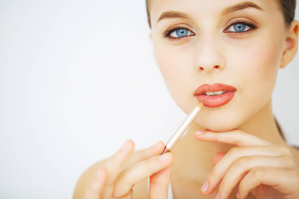 Young woman applying lipstick