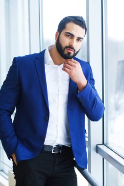 Pencere kenarındaki yüz düşünülmüş bir ifade ile başarılı bir genç iş adamı standları