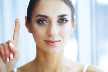 Sağlık ve güzellik. Kontakt lensler ile güzel genç kız. Kadın onu parmağına yeşil Kontakt Lens tutar. Sağlıklı görünüm. Yüksek çözünürlük