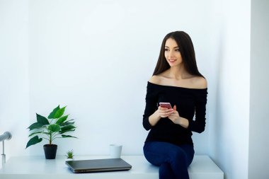 İş ev. Evde çalışıyorum. Güzel genç kadın bilgisayarda çalışıyor. Siyah ceket ve kot giymiş. Kız masa ve elinde tutan bilgisayar oturur. Yüksek çözünürlük