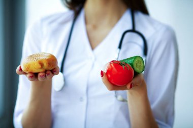Sağlık ve güzellik. Diyetisyen taze meyve ve sebze elinde tutar. Güzel bir gülümseme ile genç doktor. Yüksek çözünürlük