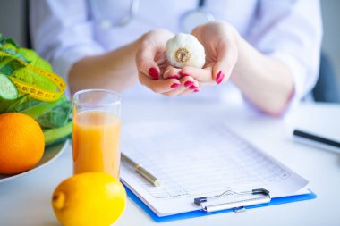 Diyet. Beslenme uzmanı doktor ofisinde sarımsak tutun. Kavramı doğal gıda ve sağlıklı bir yaşam tarzı. Fitness ve sağlıklı gıda diyet kavramı. Dengeli beslenme sebze ile.