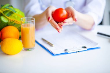 Diyet. Beslenme uzmanı doktor ofisinde domates tutun. Kavramı doğal gıda ve sağlıklı bir yaşam tarzı. Fitness ve sağlıklı gıda diyet kavramı. Dengeli beslenme sebze ile.