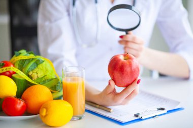 Diyet. Doktor beslenme uzmanı iş yerinde kırmızı elma tutun. Kavramı doğal gıda ve sağlıklı bir yaşam tarzı. Fitness ve sağlıklı gıda diyet kavramı. Dengeli beslenme sebze ile.