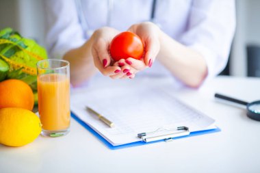 Diyet. Beslenme uzmanı doktor ofisinde domates tutun. Kavramı doğal gıda ve sağlıklı bir yaşam tarzı. Fitness ve sağlıklı gıda diyet kavramı. Dengeli beslenme sebze ile.