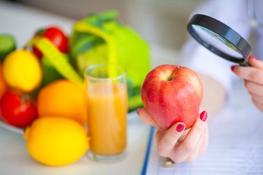 Diyet. Doktor beslenme uzmanı iş yerinde kırmızı elma tutun. Kavramı doğal gıda ve sağlıklı bir yaşam tarzı. Fitness ve sağlıklı gıda diyet kavramı. Dengeli beslenme sebze ile.