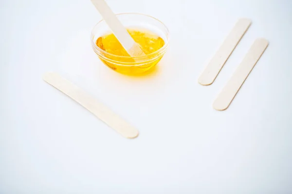 Waxing. Paste for sugaring in beauty salon. Concept depilation with wax and sticks on white background top view.